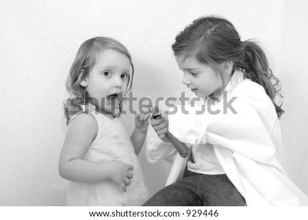 Cute little girls with a white doctor\'s coat and a tongue depressor