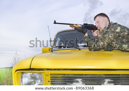 Sniper in camouflage on car at sunset outdoor.