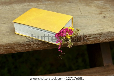 Closed book with flowers on wood table background horizontal