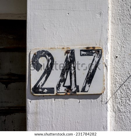 House number two hundred and forty seven. Black lettering on a white background.