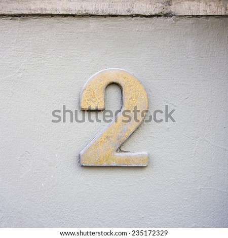 metal house number two on a white stucco wall