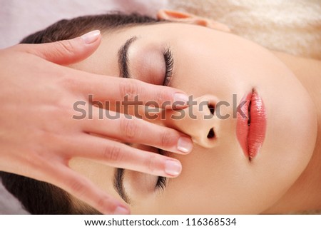 Beautiful young relaxed woman enjoy receiving face massage at spa saloon