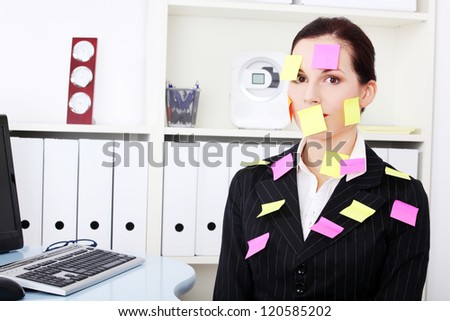 Beautiful caucasian businesswoman sitting in the office with post it notes on her body.
