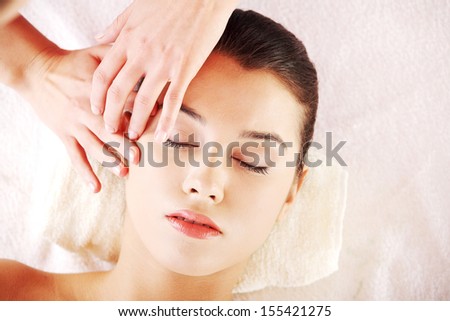 Beautiful young relaxed woman enjoy receiving face massage at spa