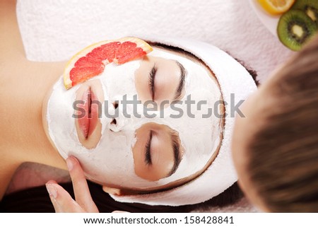 Attractive young woman with fruit mask on a face at spa saloon