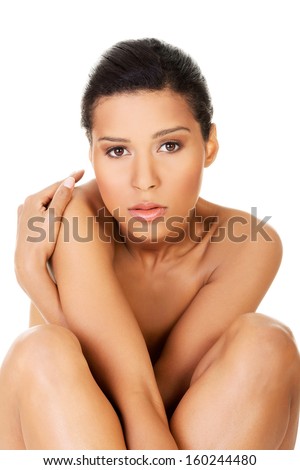 Beautiful and naked women sitting and covering her nudity by her legs and arms. Front view. . Isolated on white.