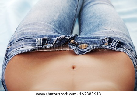 Woman\'s belly, open jeans. Up front view.Isolated on white.
