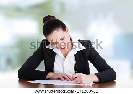 Beautiful attractive corporate lawyer business woman sitting at desk and writing blank paper page.