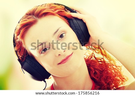 Attractive smiling redhead woman with headphones listening music