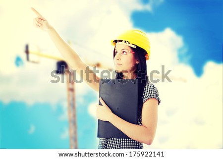 Engineer woman in yellow helmet pointing on something