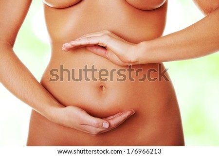 Front view of a fit belly closeup and hands forming a circle around the navel, over white.