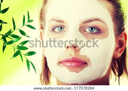 Cosmetics mask of clay on the  young female face, against abstract green background