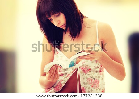 Pretty young girl in pyjamas with book in hands.