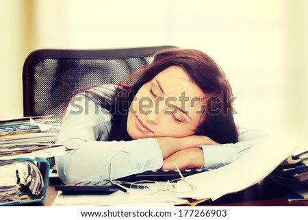 Exhausted female filling out tax forms while sitting at her desk.