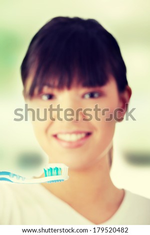 Young beautiful woman washing her teeth with blue brush, isolated on white background - focus on brush