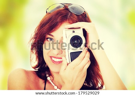 Young beautiful smiling woman holding a micro four thirds photo camera.