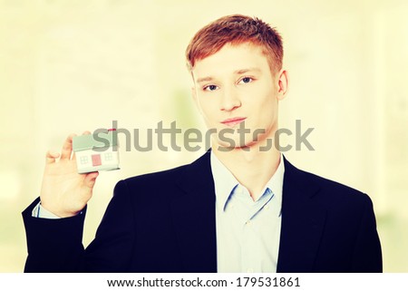 Young business man holding house model - real estate concept.