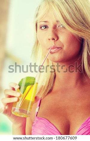 Beautiful young woman in pink bikini with cold drink (green tea)