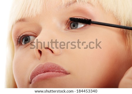 Close up on beautiful young woman doing make up on eyelashes. Over white background.