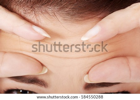 Young woman checking her wrinkles on forehead. Over white.