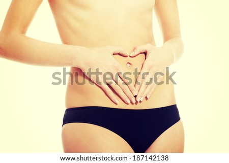 Woman is having heart shape made from hands on her belly. Isolated on white.