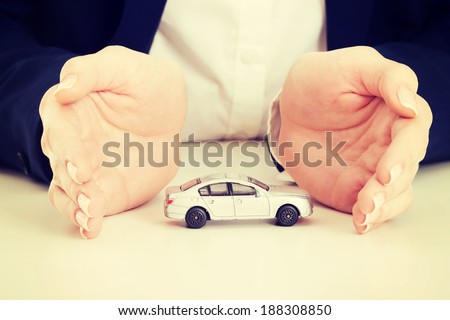 Close up on car toy model between hands lying on the table.