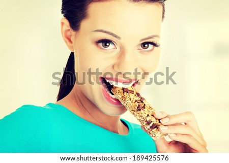 Young woman eating Cereal candy bar