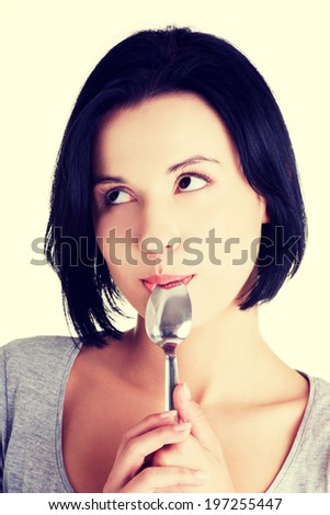 Portrait of young smiling woman with spoon in her mouth -pleasure from eating