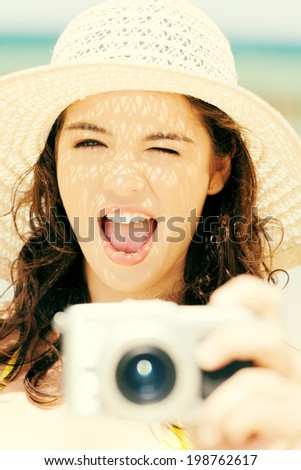Attractive cheerful summer woman talking pictures with digital camera .