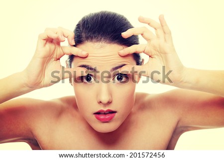 Woman checking her wrinkles on her forehead.