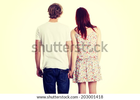 Young couple are standing a back side and holding hands.