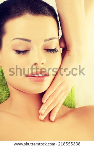 Beautiful young relaxed woman enjoy receiving face massage therapy at spa saloon