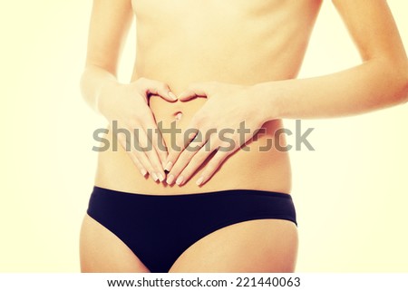 Woman is having heart shape made from hands on her belly. Isolated on white.