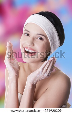 Beautiful happy woman is cleaning her face