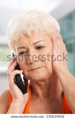Old lady talking through phone, receiving bad news.