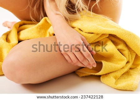 Close up on woman sitting wrapped in yellow towel.