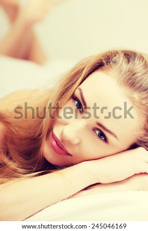 Portrait of beautiful caucasian woman lying in bed with her legs up.
