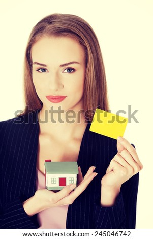 Beautiful businesswoman holding small house and personal card.