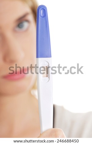 Sad young woman holding pregnancy test feeling hopeless