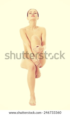 Beautiful naked woman sitting with one leg up.