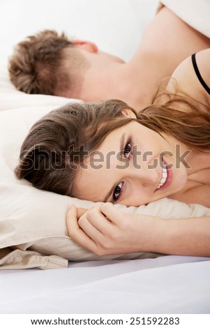 Young happy smiling woman and sleeping man in bed.