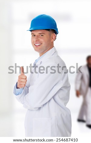 Man in a lab coat and helmet, engineer, teacher or chemical gesturing OK