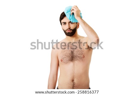 Shirtless man with headache and ice bag on his head.