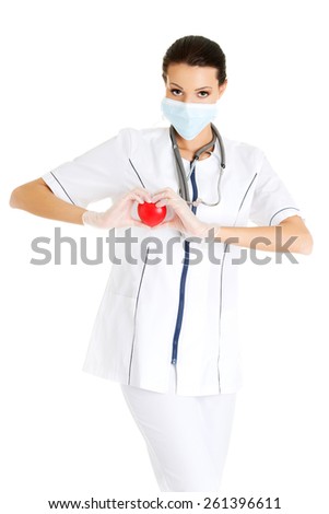 Female doctor in protecting mask holding heart model.
