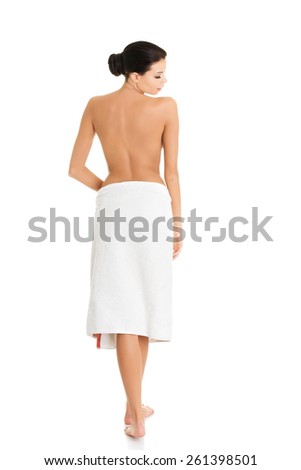 Back view nude woman standing wrapped in towel.