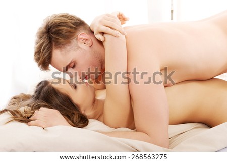 Young caucasian couple kissing on bed.