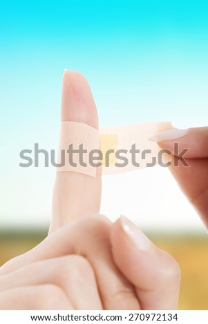 Woman apply aid plaster on finger.