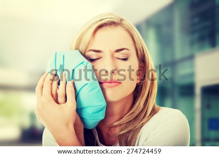 Woman with tooth ache holding an ice bag near her face