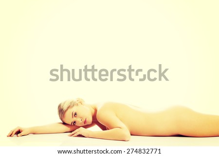 Side view of slim nude woman lying on belly, propping chin