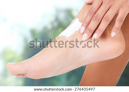 Beautiful woman applying lotion on foot.